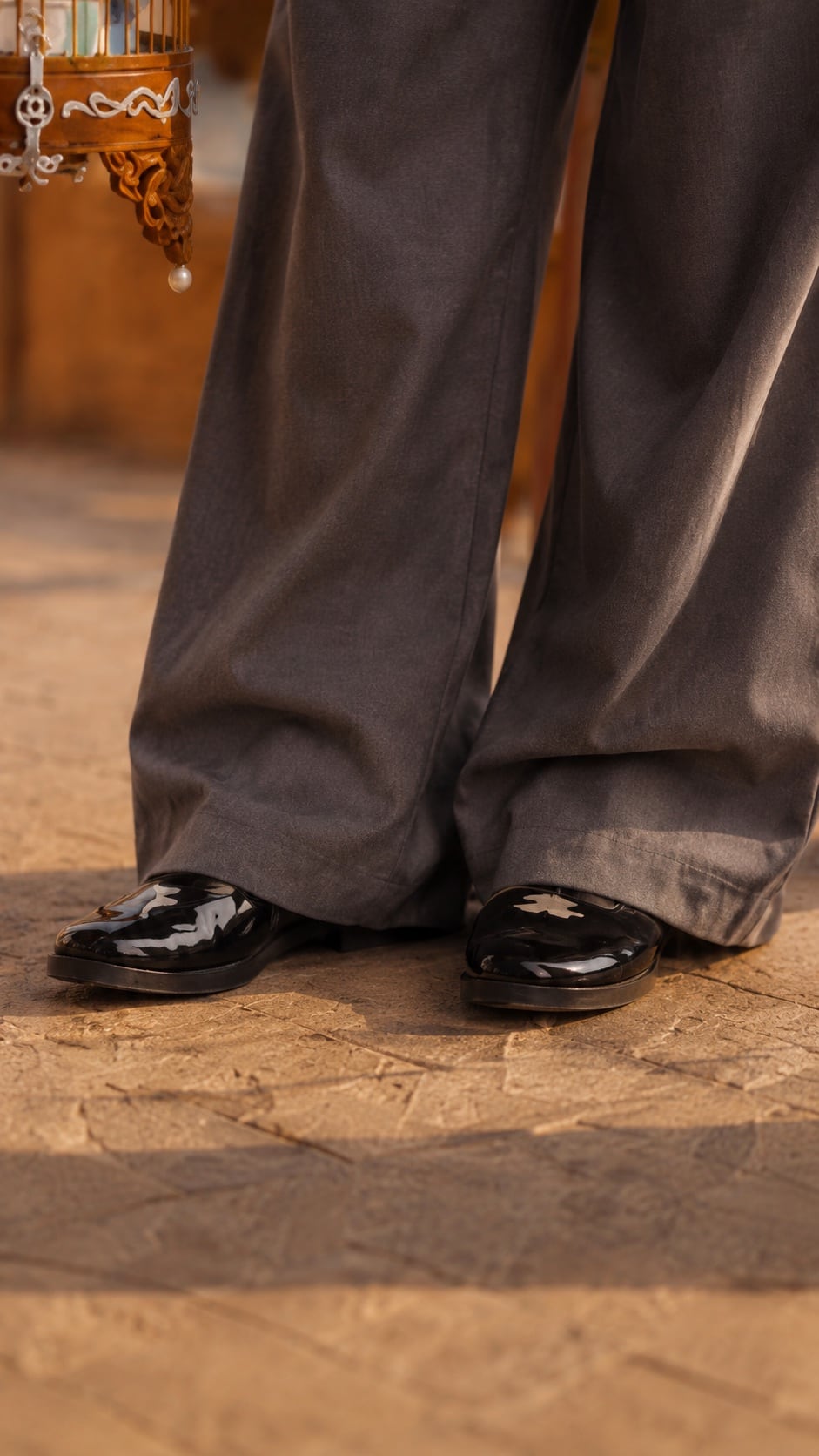 Close-up styling detail with black shoes and wide-leg trousers
